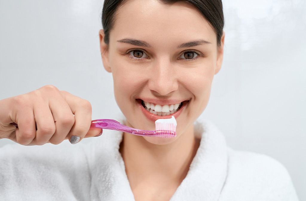 Woman brushing her teeth as part of a healthy oral hygiene routine